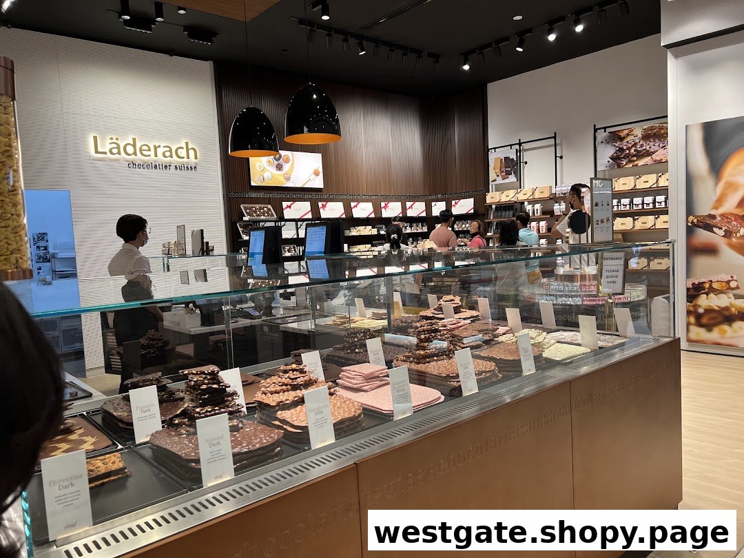 Interior view of a Läderach chocolate shop with a large display of fresh chocolate slabs and customers.