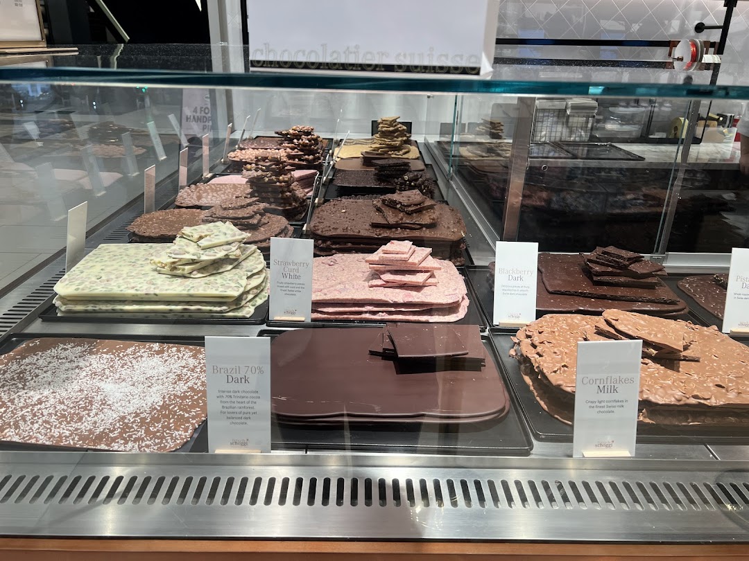 A vibrant display case showcasing various artisanal chocolate slabs and bark at Läderach.