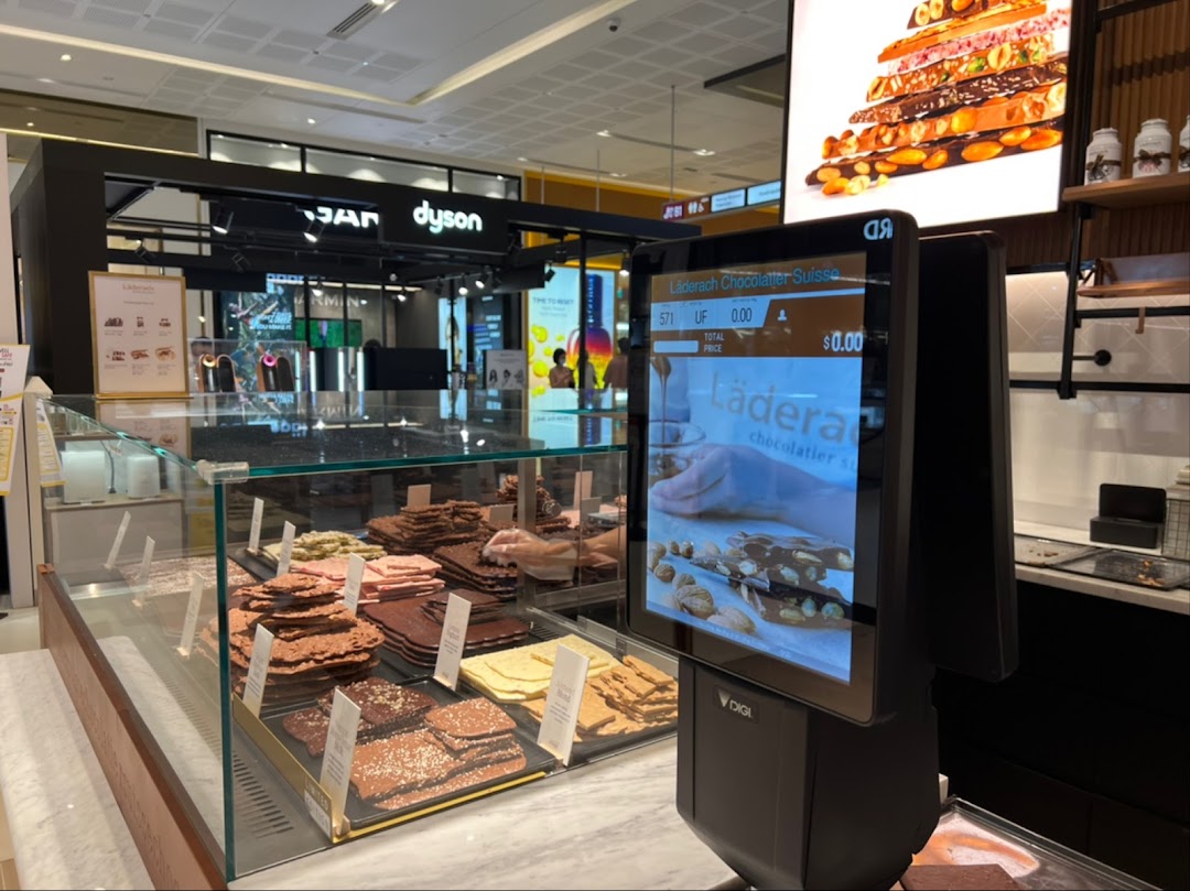 A display counter at Läderach Chocolatier Suisse, showcasing various fresh chocolate slabs and pralines.