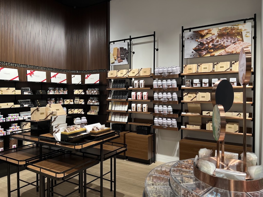 Interior view of Läderach chocolate shop showcasing shelves filled with various chocolate products and gift boxes.