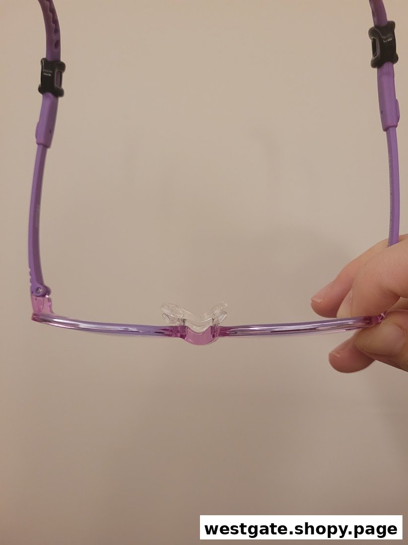 A close-up of purple eyeglasses with a clear nose bridge, held by a hand.
