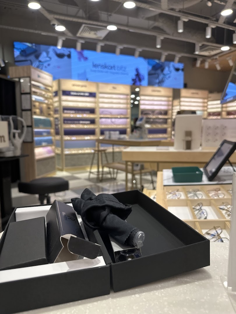 Interior view of Lenskart showcasing eyewear displays, a large digital screen, and a product box on the counter.