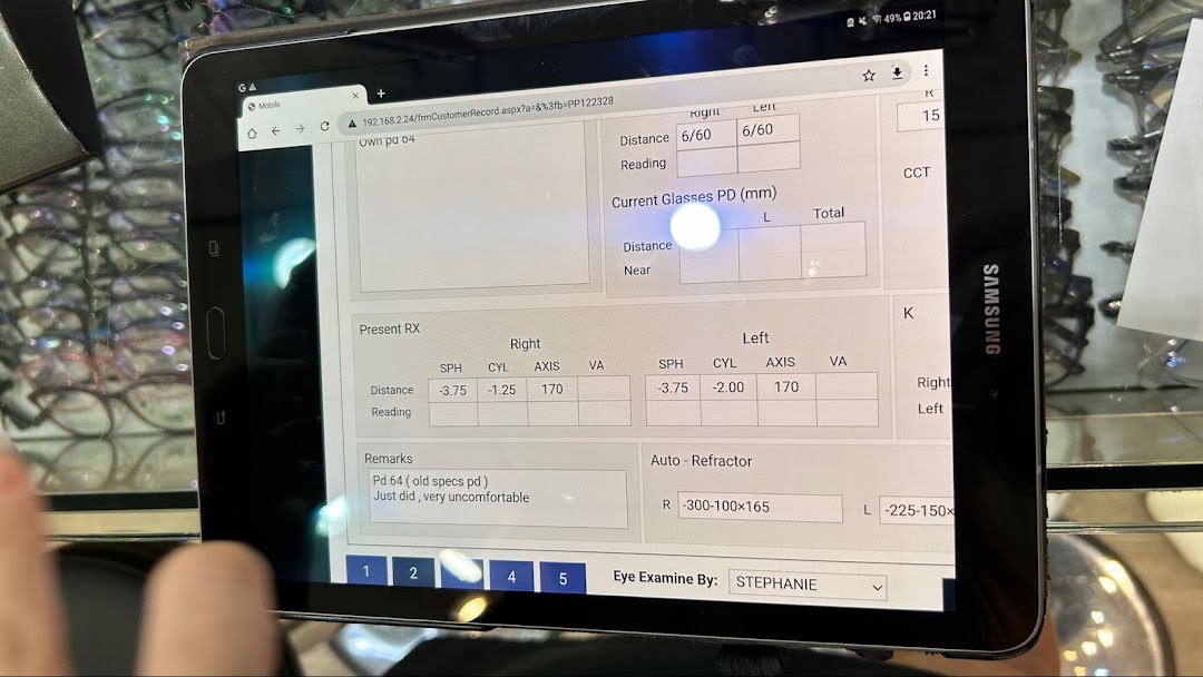 A tablet displays eye examination results and customer data at Lenskart, with eyeglasses visible in the background.