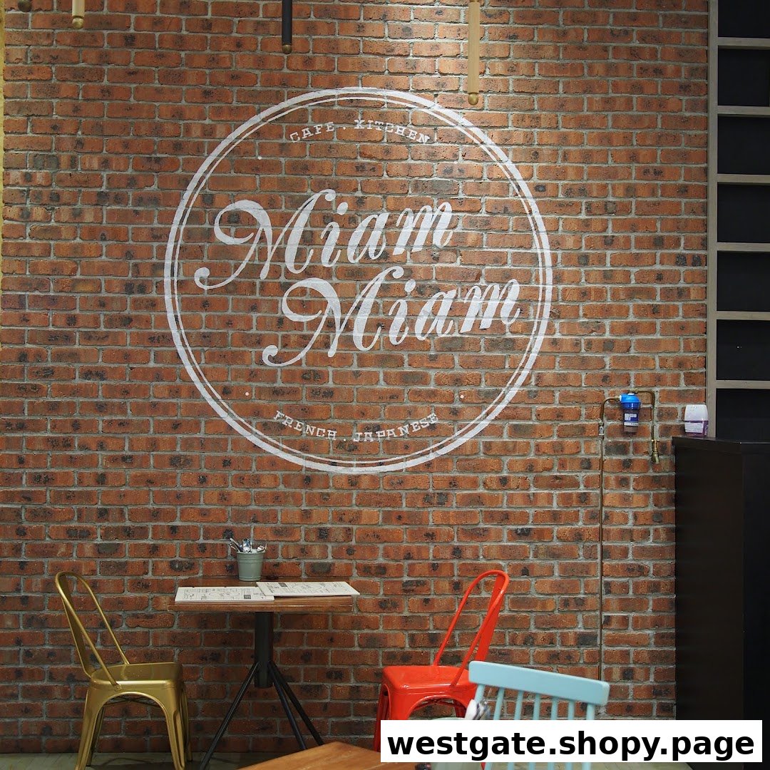 Interior view of Miam Miam cafe featuring a brick wall with its French-Japanese logo and seating.