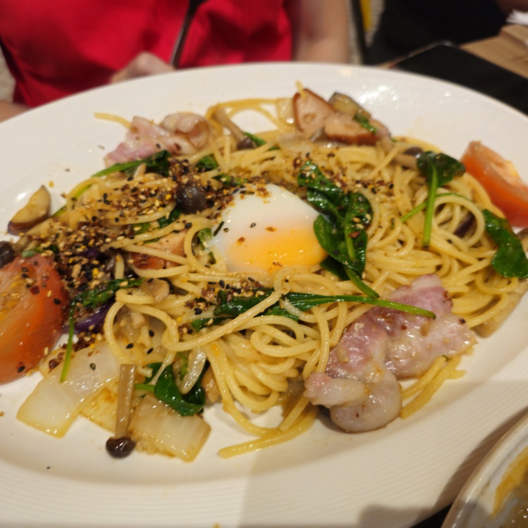 A close-up of a delicious pasta dish with bacon, vegetables, and a poached egg.