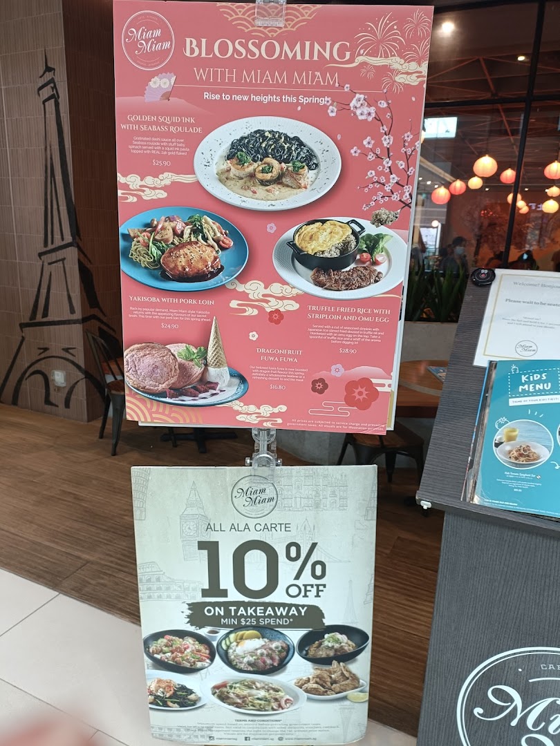 A promotional stand outside Miam Miam French Japanese Cafe Kitchen, showcasing spring specials and a takeaway discount.