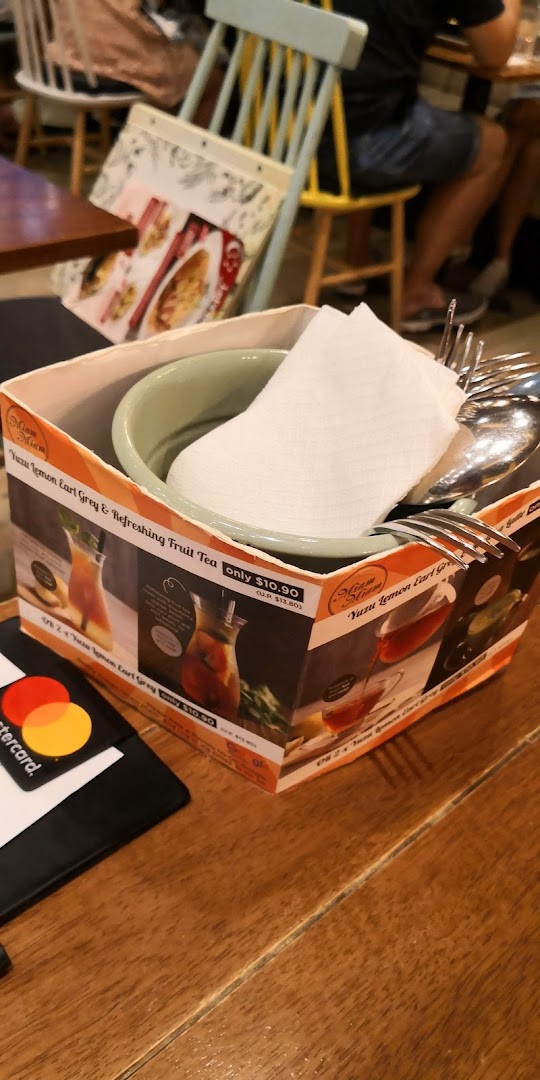 A close-up of a table setting featuring a utensil holder with promotional drink offers from Miam Miam.