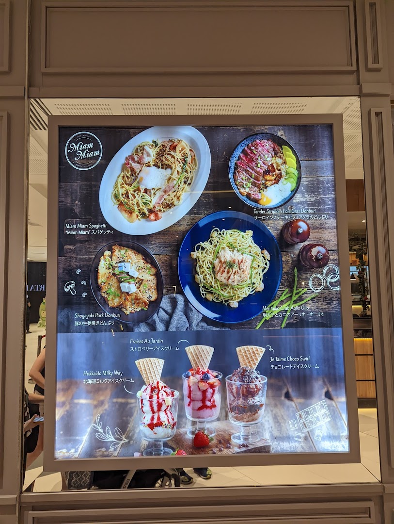 A brightly lit display board showcasing Miam Miam's French-Japanese fusion dishes and delightful desserts.