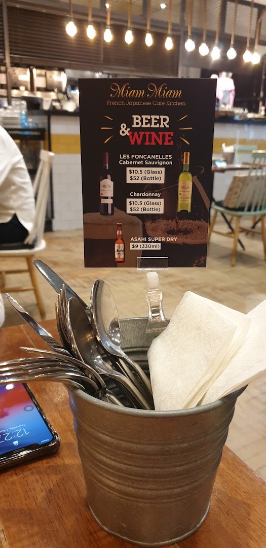 A close-up of a table-top menu displaying beer and wine options with prices at Miam Miam.