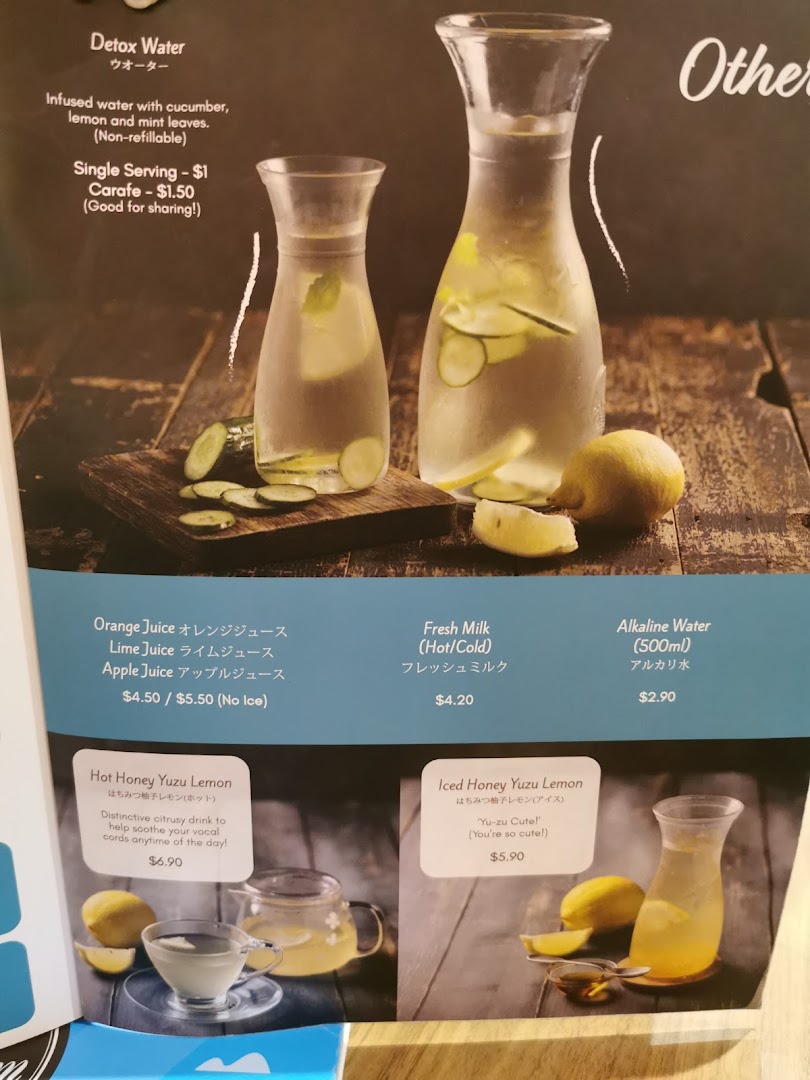 A close-up of a cafe menu featuring various refreshing drinks like detox water, juices, and honey yuzu lemon.