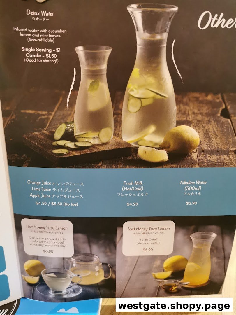 A close-up of a cafe menu featuring various refreshing drinks like detox water, juices, and honey yuzu lemon.