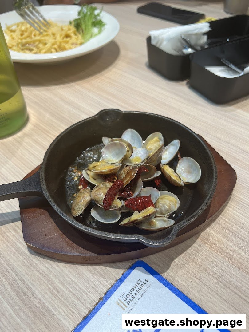 A close-up of a sizzling clam dish and pasta on a wooden table in a restaurant setting.
