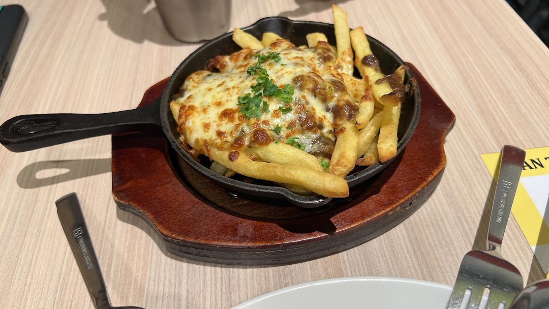 A cast iron skillet filled with golden fries topped with melted cheese and gravy.