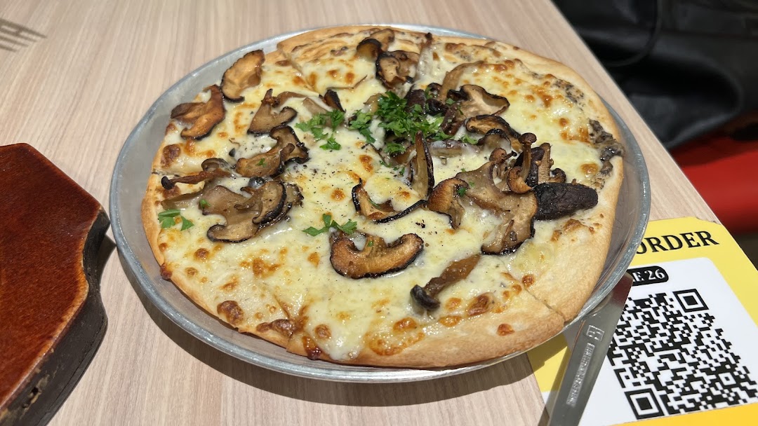 A delicious mushroom pizza with melted cheese and fresh herbs on a table, ready to be enjoyed.