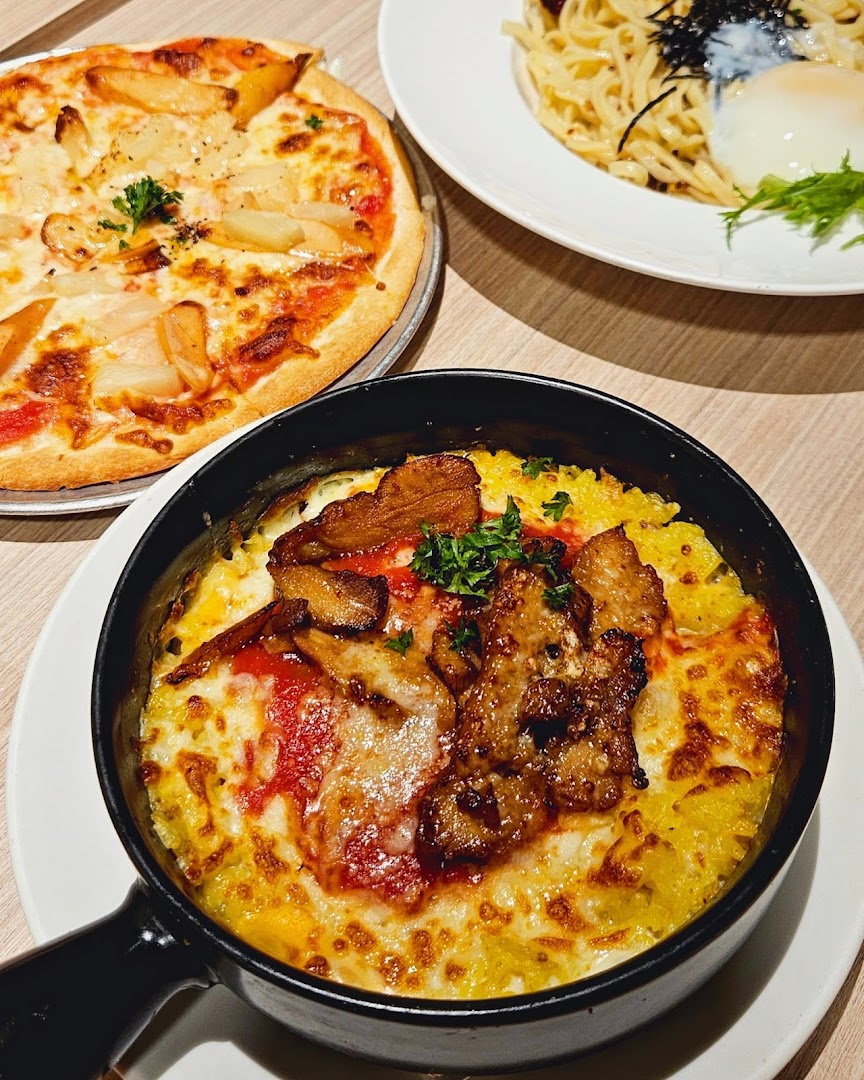 A delicious spread of Italian-Japanese fusion dishes, including pizza, baked rice, and pasta.
