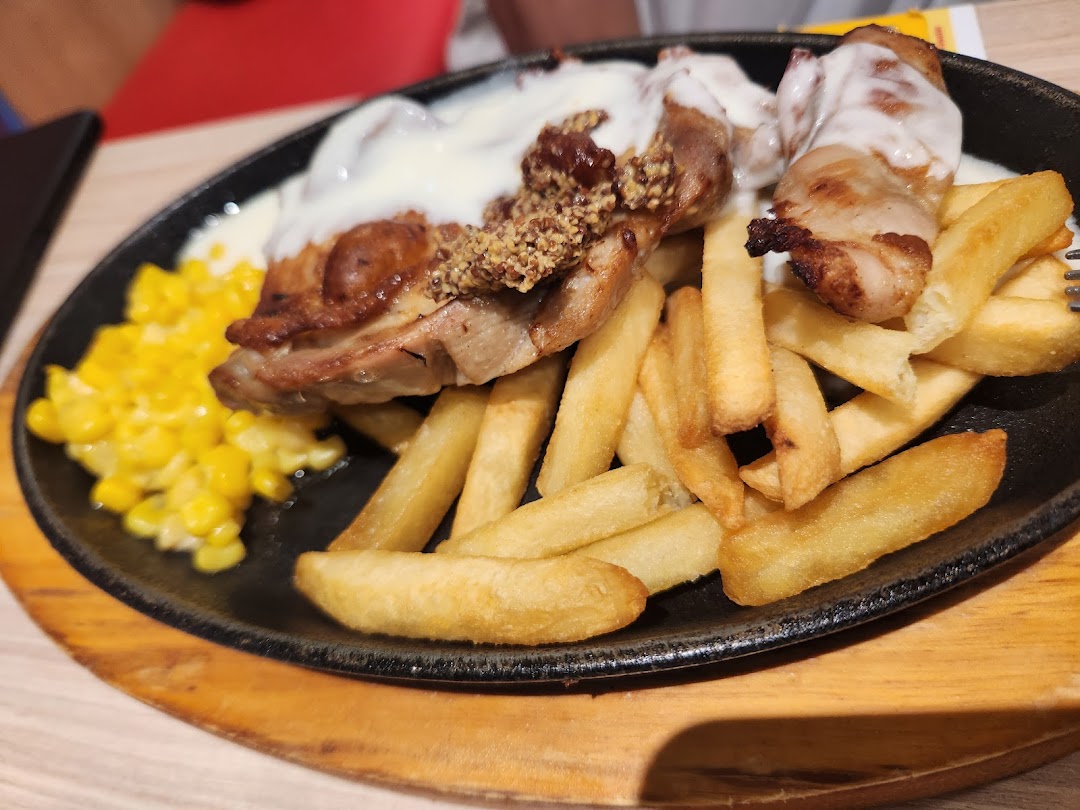 A sizzling plate featuring grilled chicken with sauce, golden fries, and sweet corn.