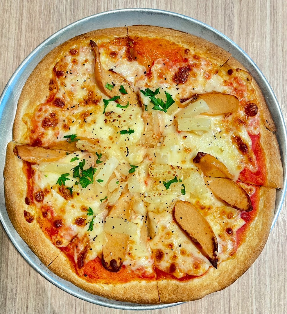 A delicious pizza topped with melted cheese, sausage slices, and pineapple chunks on a metal tray.