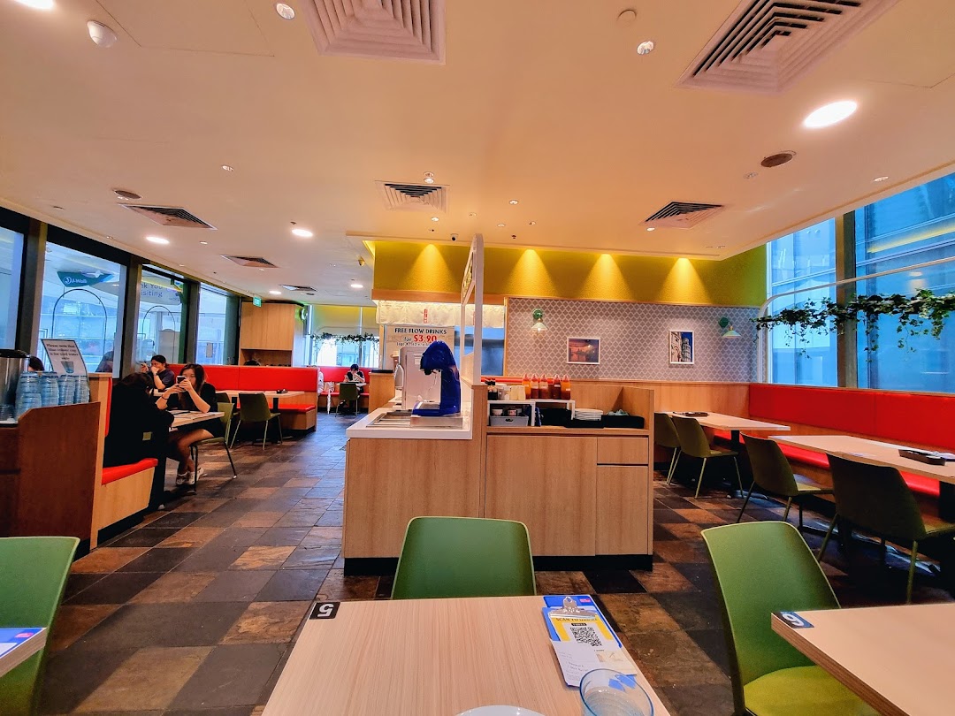 A bright and spacious interior of Milan Shokudo with comfortable seating and a self-service drink station.