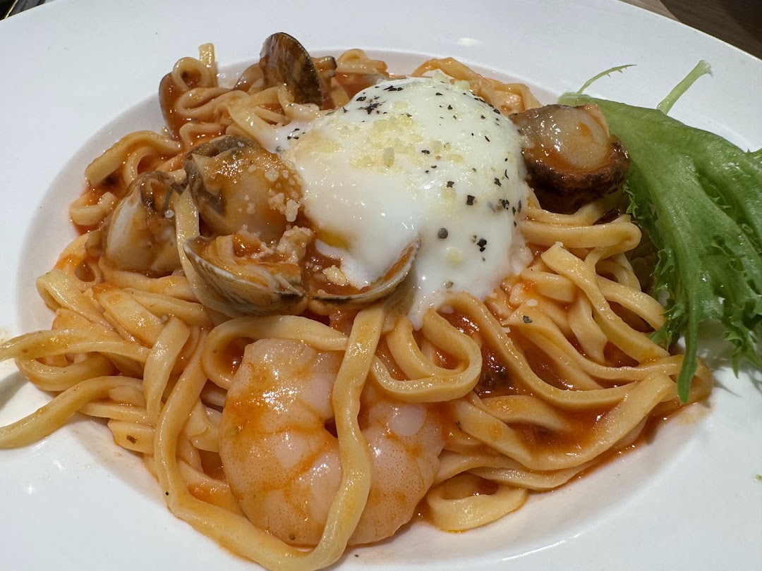 Close-up of a delicious seafood pasta dish with shrimp, clams, and a poached egg.
