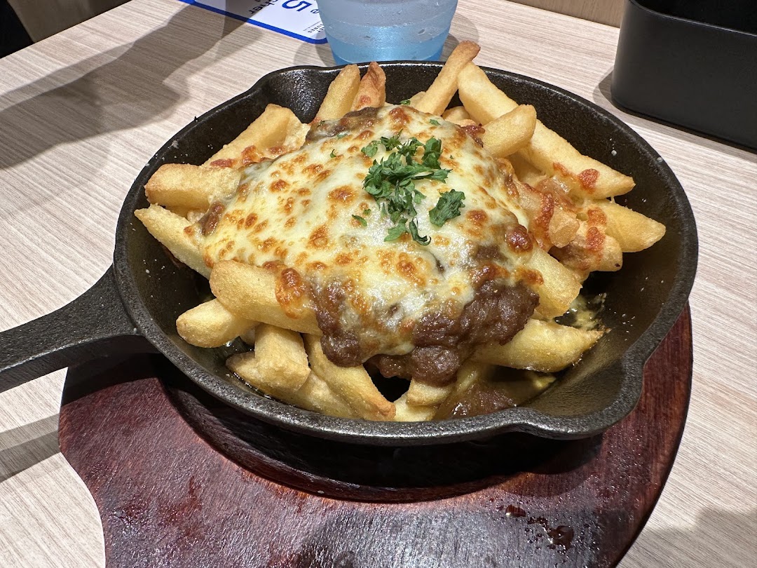 A close-up of crispy french fries topped with savory meat sauce and melted cheese in a skillet.