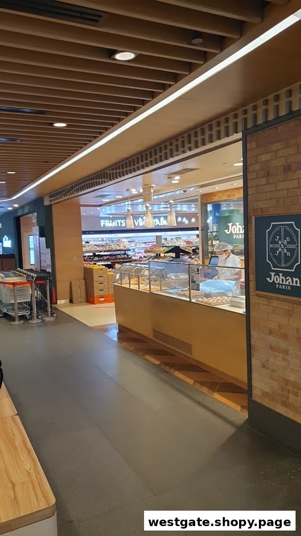 View of the Johan Paris bakery counter at the entrance of a supermarket, with fresh produce visible inside.