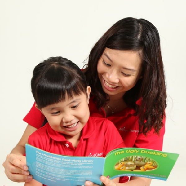 A teacher and child in red shirts happily read 'The Ugly Duckling' book.