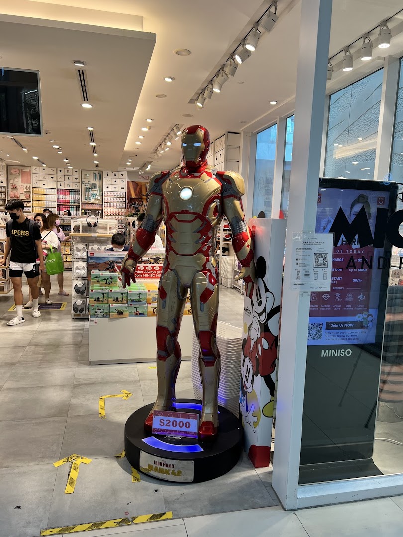 An Iron Man statue stands prominently inside a MINISO store, with shoppers browsing products.