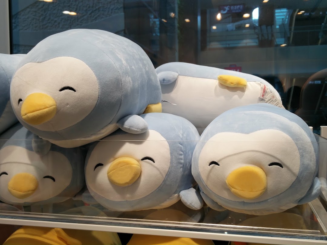 A display of adorable light blue penguin plush toys with happy faces at MINISO.