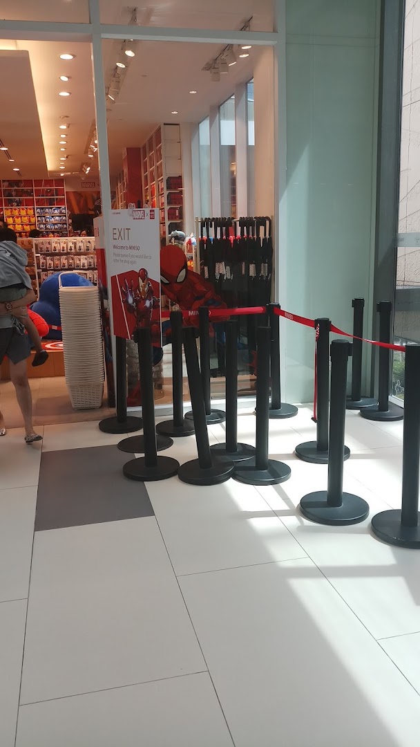 The entrance of MINISO Westgate features queue barriers, an 'EXIT' sign with Marvel characters, and a glimpse into the store's vibrant interior.