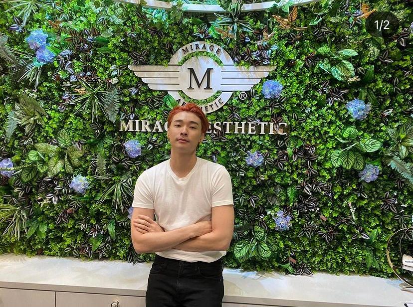 A man stands in front of a lush green wall featuring the Mirage Aesthetic logo.