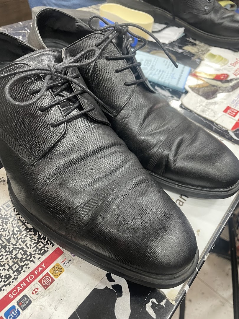 Close-up of black shoes on a counter, ready for repair or service at Mister Minit.