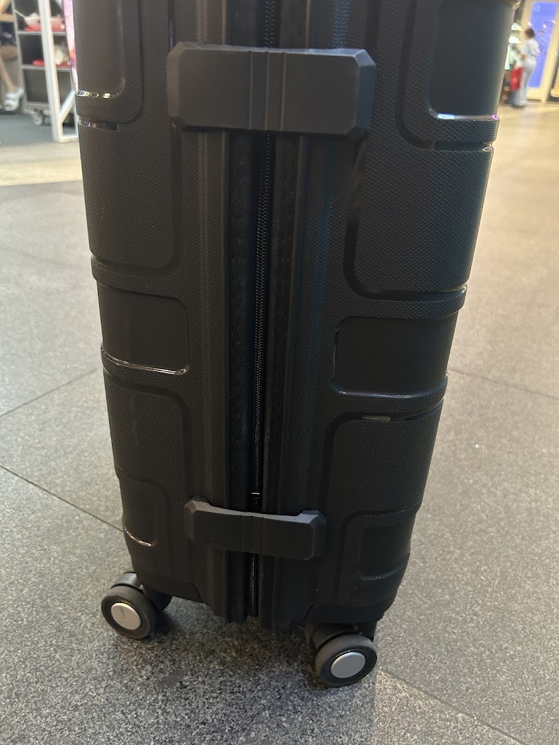 Close-up of a black, textured suitcase with wheels on a tiled floor.
