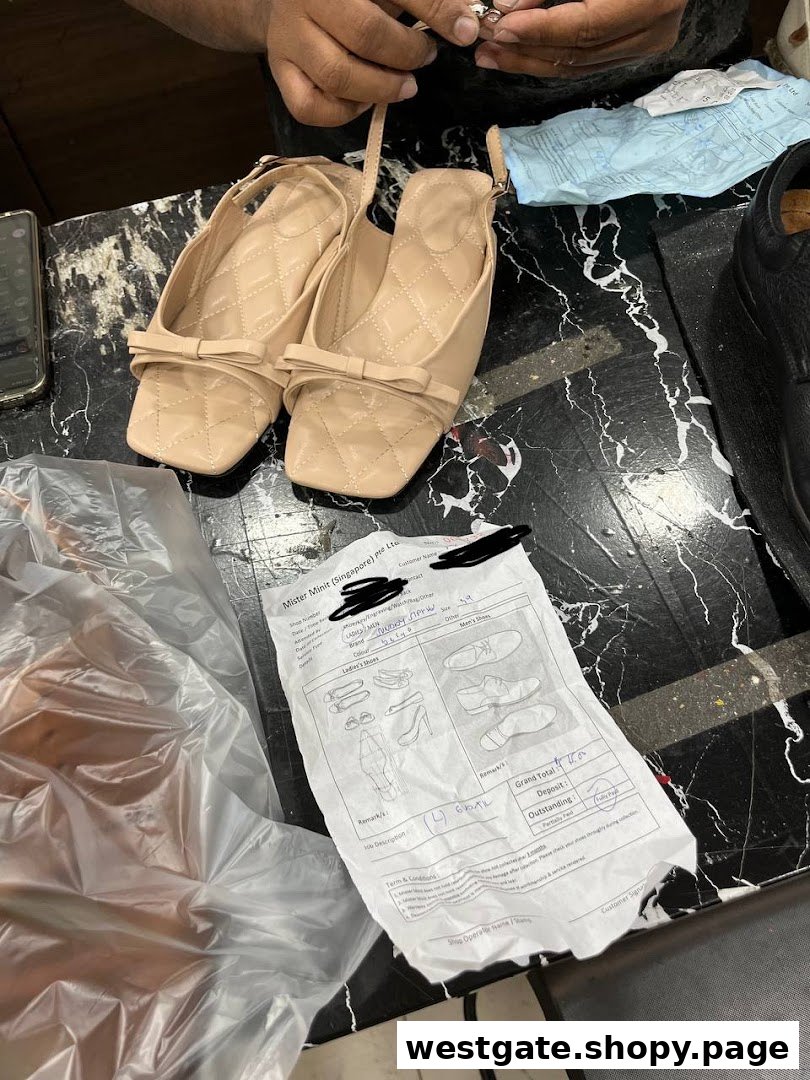 A pair of beige shoes on a counter with a service form and hands working on an item.