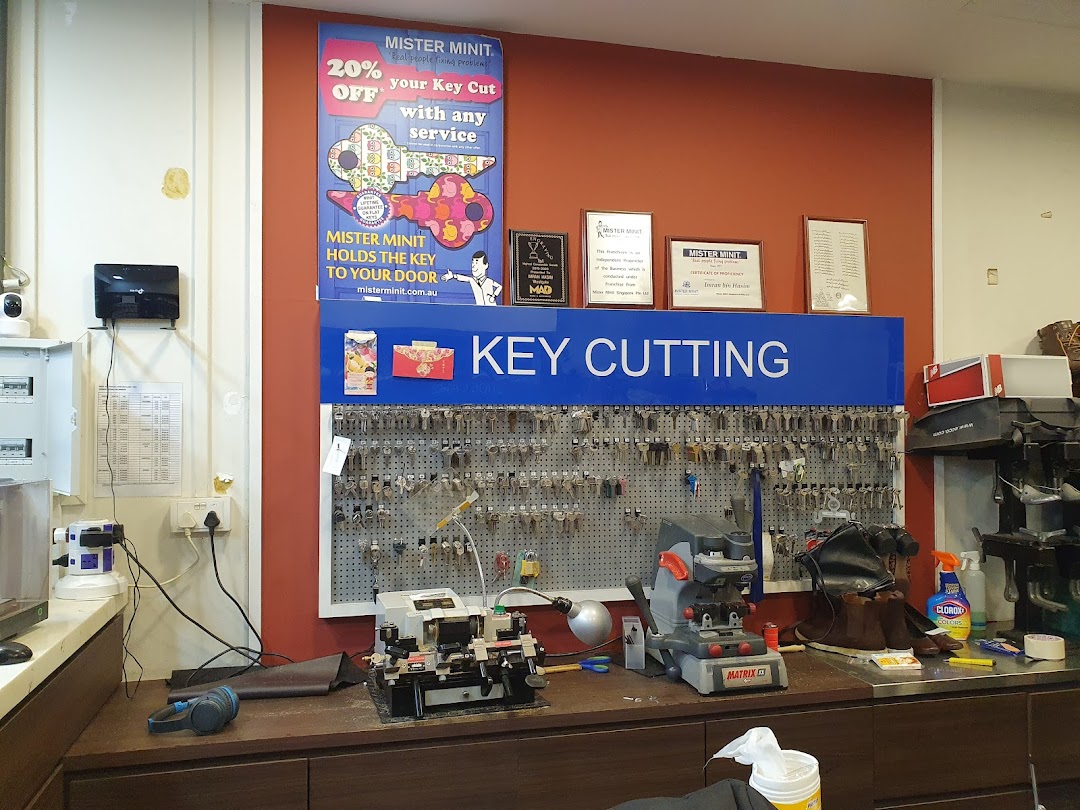 Interior view of Mister Minit's key cutting station, showing machines, a key display, and promotional signage.