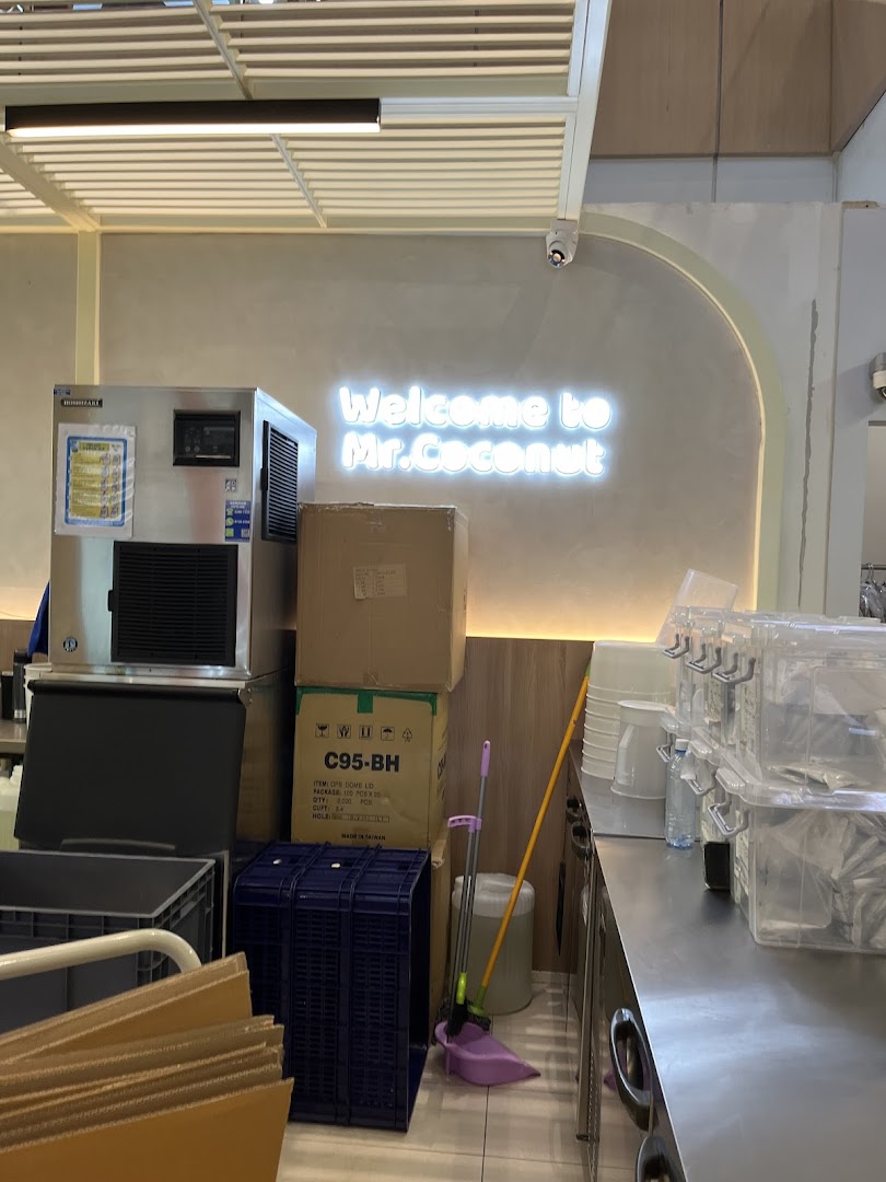 Interior view of Mr. Coconut showing equipment, storage, and a neon 'Welcome' sign.