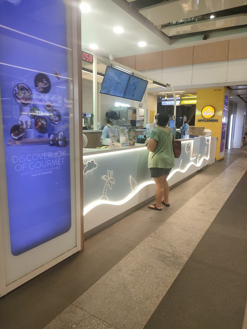 A customer orders at the counter of Mr. Coconut, a beverage shop, with digital menu screens visible.