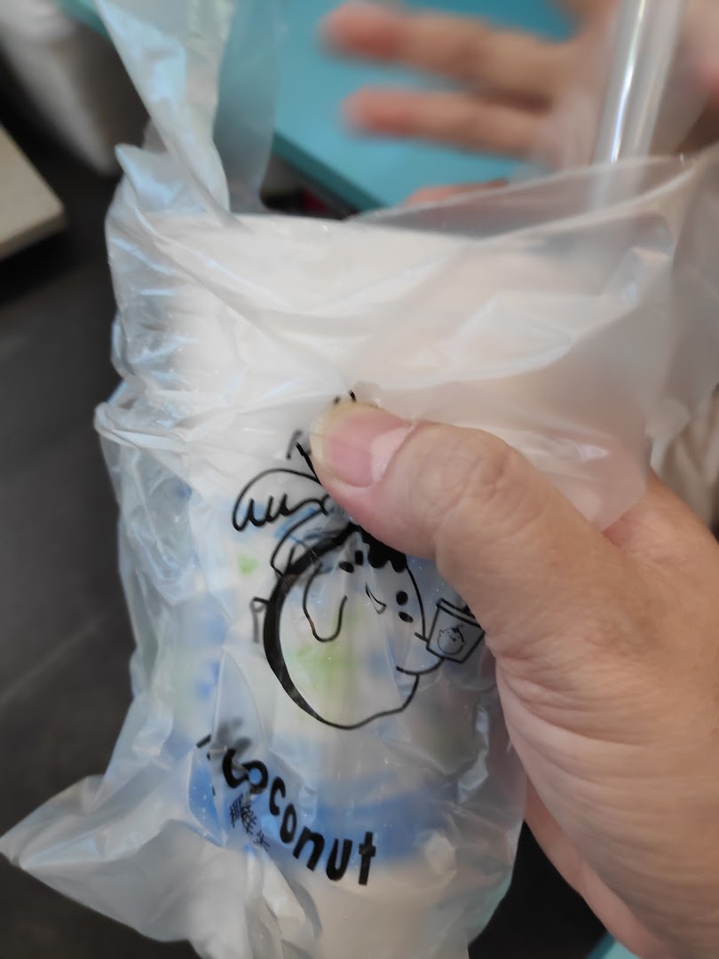 A hand holds a Mr. Coconut drink in a clear plastic bag with the brand's logo.