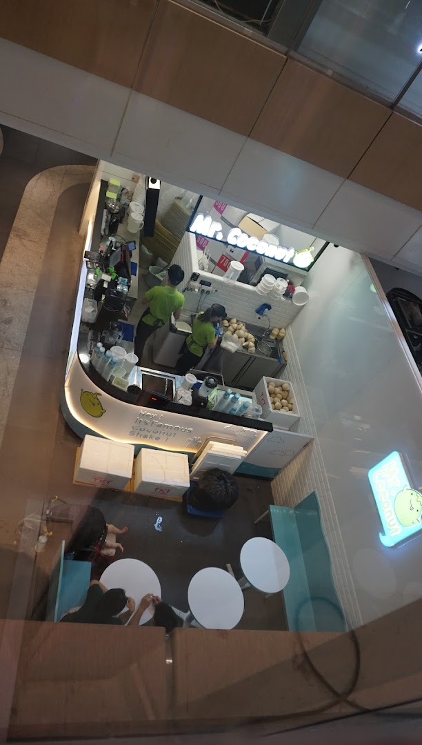 An overhead view of Mr. Coconut shop, showing staff preparing fresh coconut drinks and a small seating area.