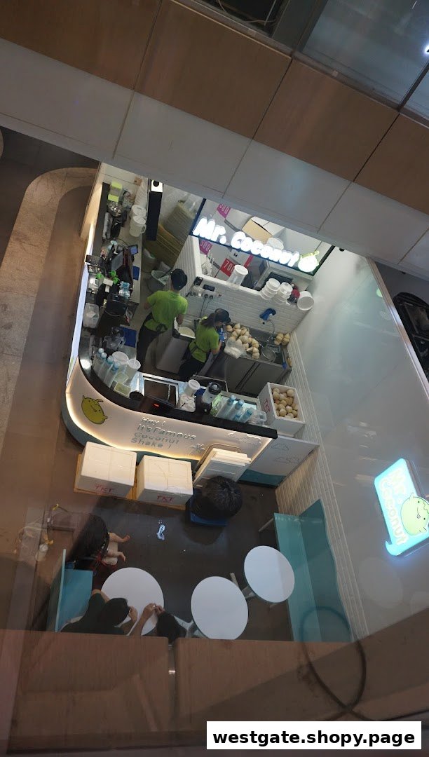 An overhead view of Mr. Coconut shop, showing staff preparing fresh coconut drinks and a small seating area.