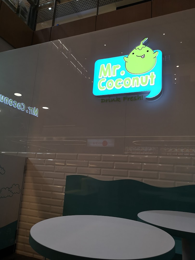 Illuminated Mr. Coconut shop sign featuring its mascot and 'Drink Fresh!' slogan, with interior seating.