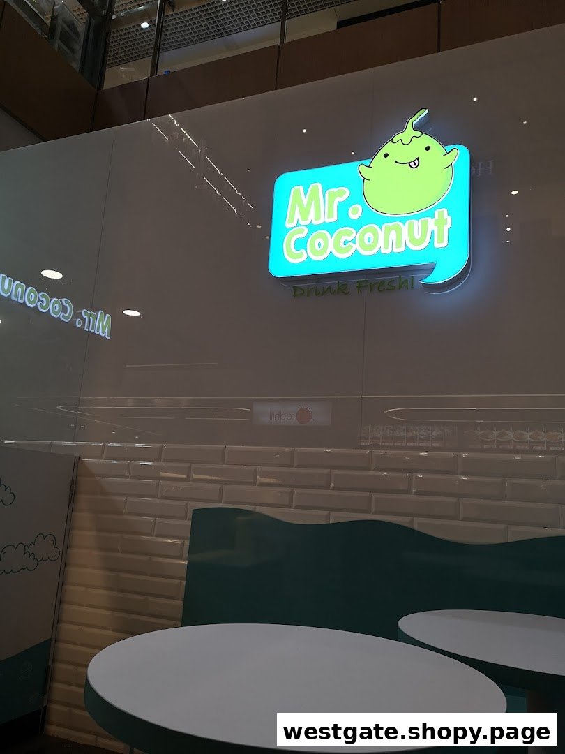 Illuminated Mr. Coconut shop sign featuring its mascot and 'Drink Fresh!' slogan, with interior seating.