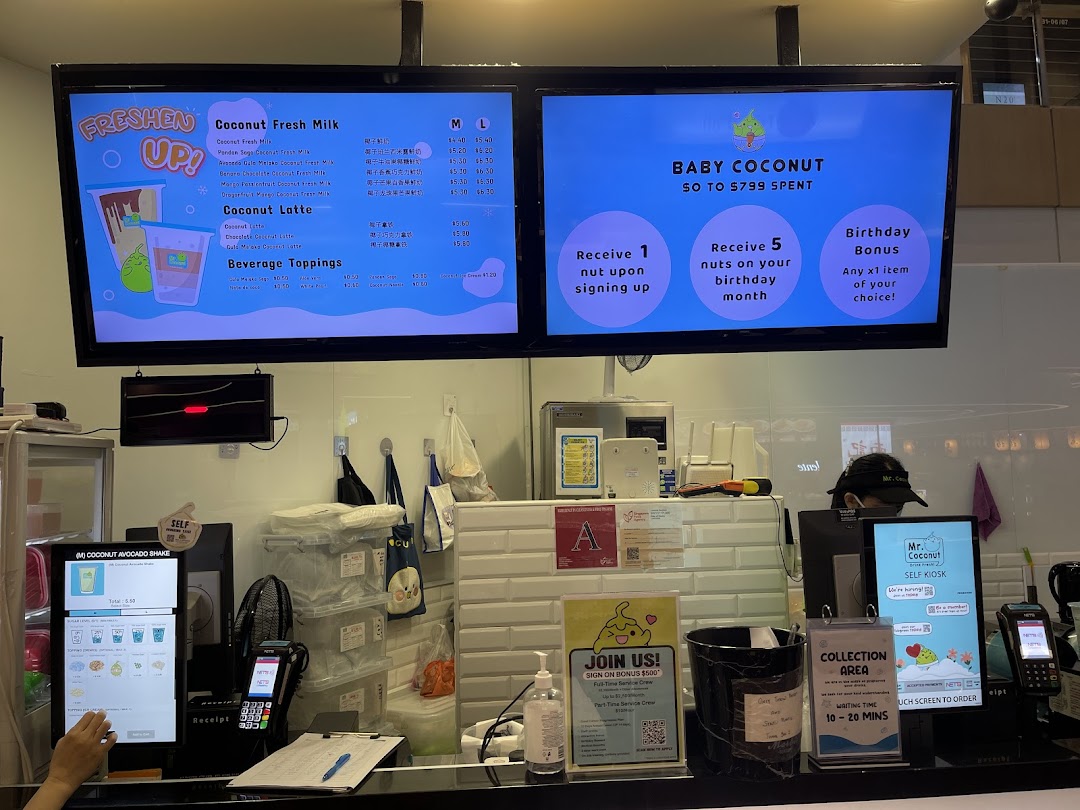Digital menu boards and a self-service kiosk display coconut-based drinks and loyalty program details at Mr. Coconut.