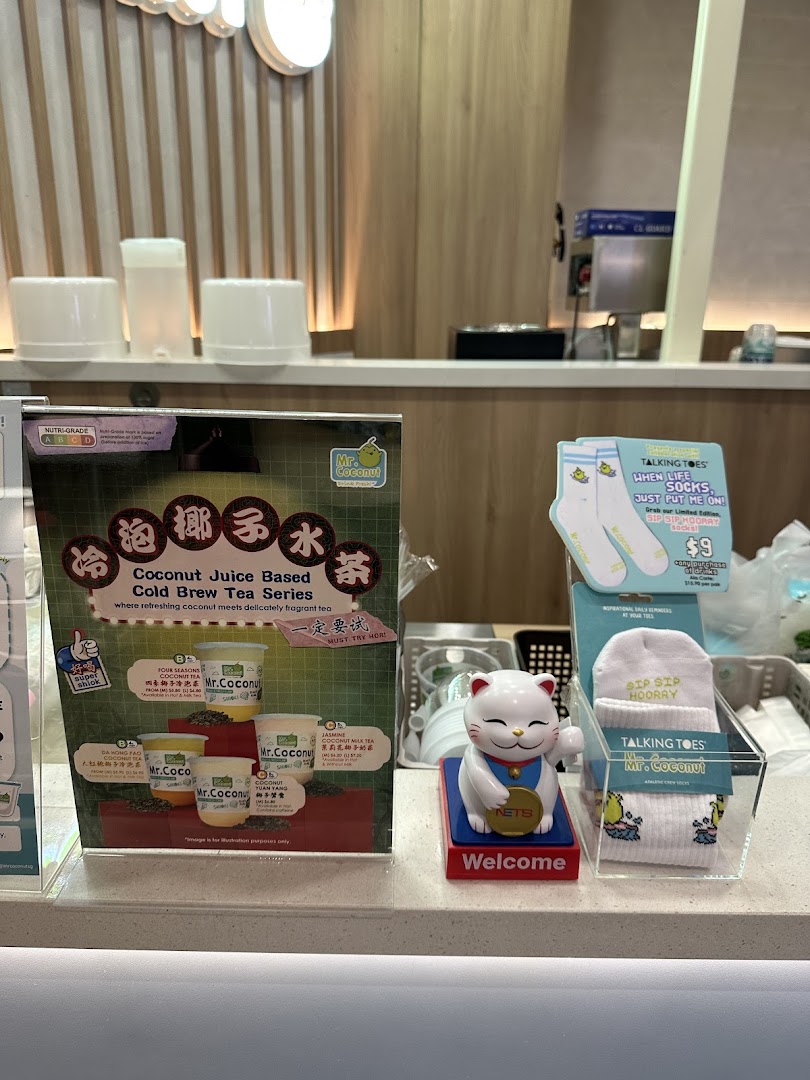 A Mr. Coconut counter featuring a cold brew tea series display, a Maneki-neko cat, and branded 'Talking Toes' socks.