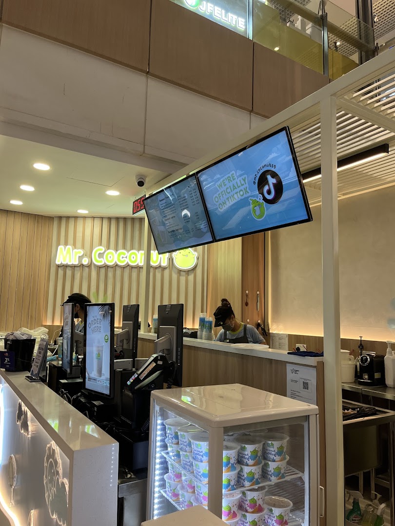 Interior view of Mr. Coconut shop, showing the service counter, staff, and digital displays.