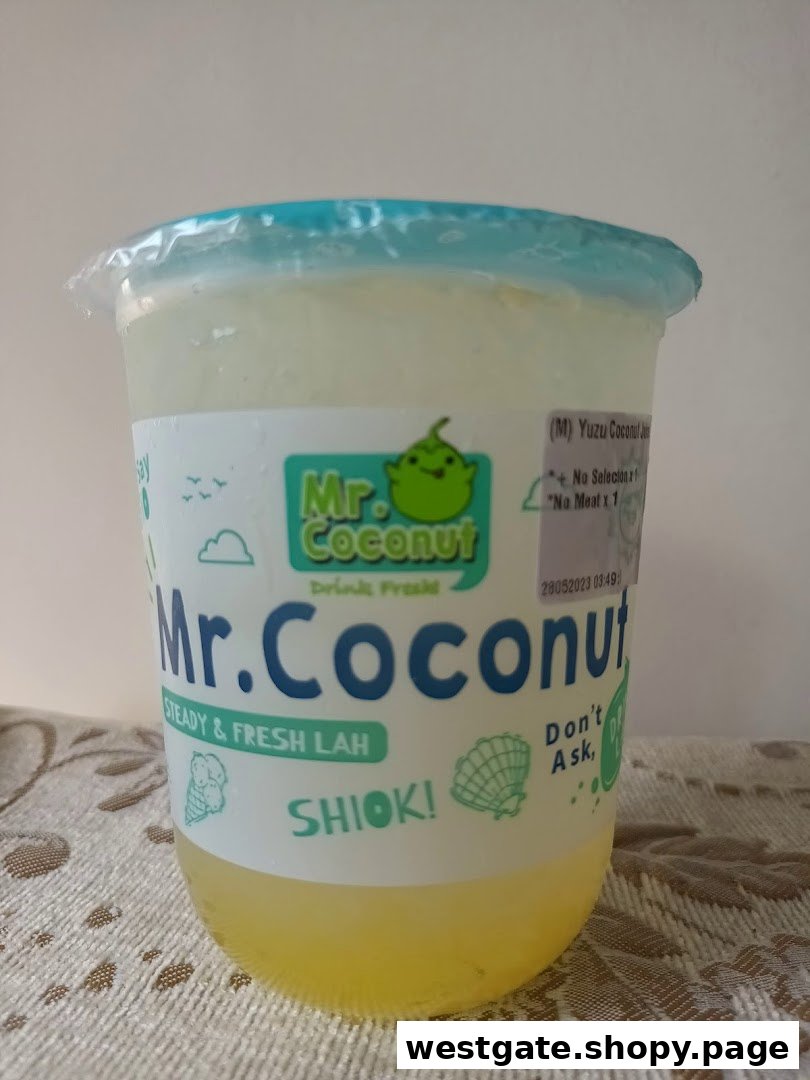 A clear plastic cup of Yuzu Coconut drink from Mr. Coconut, featuring the brand's logo and slogans.