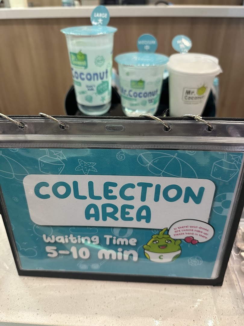 A Mr. Coconut collection area sign with various drink cups and a waiting time display.