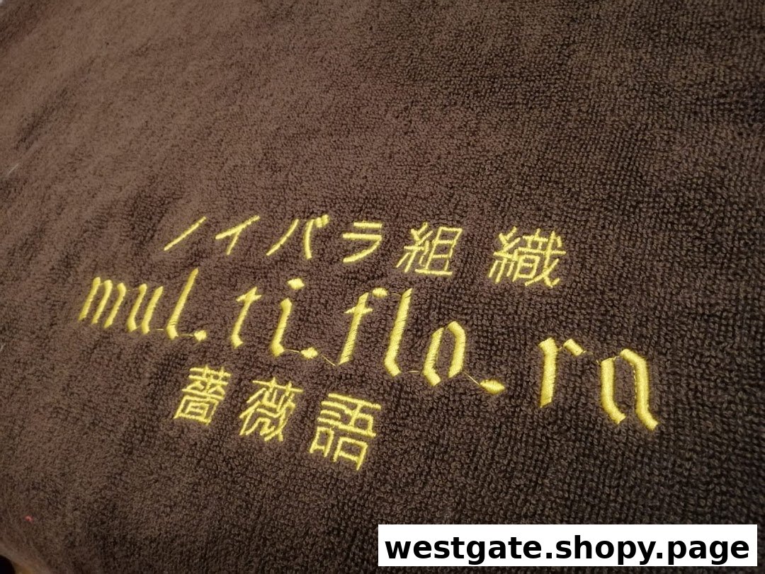 Close-up of a brown towel with 'multiflora' and Japanese text embroidered in yellow.