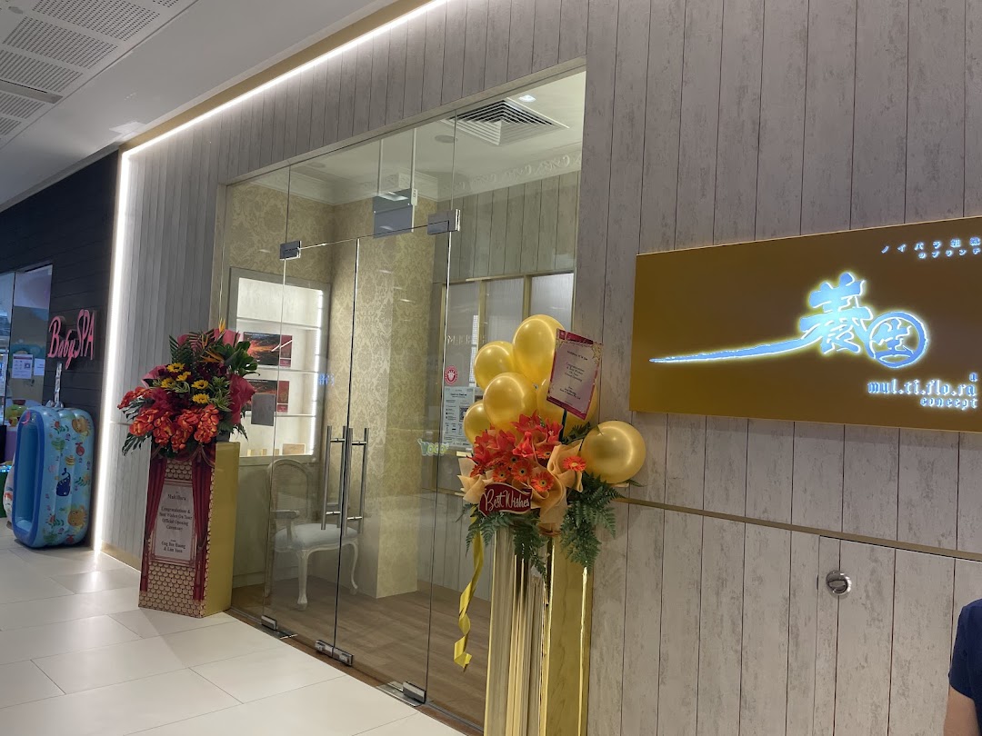 The inviting entrance of Multiflora TCM Spa, adorned with floral arrangements and balloons, featuring its illuminated sign.