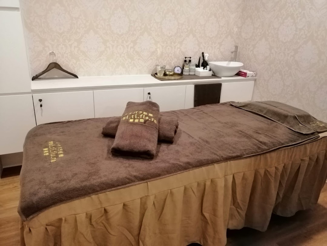 A serene spa treatment room featuring a massage bed, towels, and a wash basin.