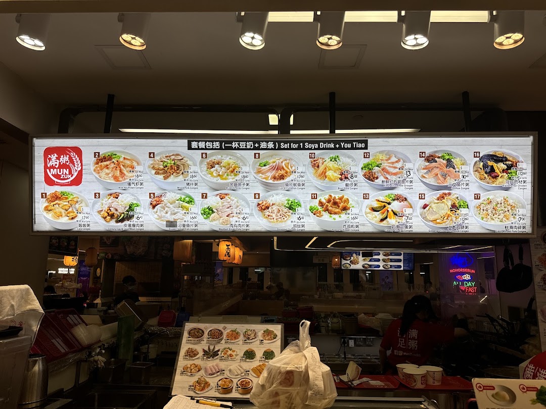 A brightly lit menu board displaying various congee dishes and their prices above a bustling shop counter.